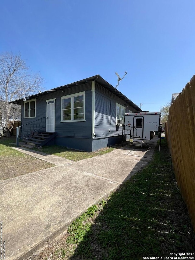 view of front of property featuring cooling unit, entry steps, driveway, and fence