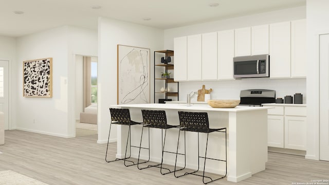 kitchen with a center island with sink, light wood finished floors, stainless steel microwave, a kitchen breakfast bar, and range