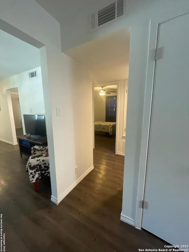 corridor with visible vents, dark wood-type flooring, and baseboards