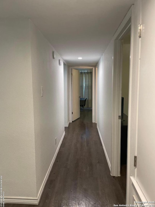 corridor featuring baseboards and wood finished floors