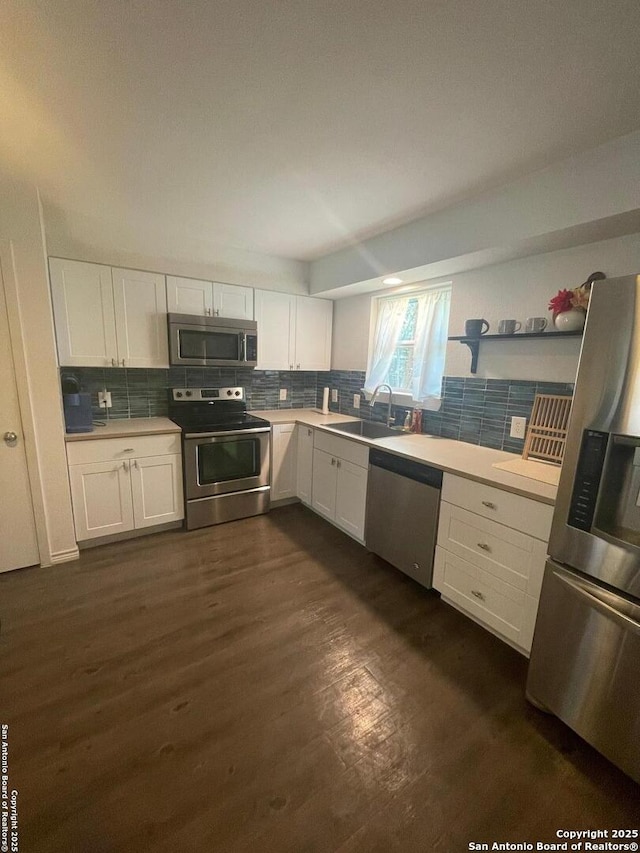 kitchen featuring dark wood-type flooring, a sink, white cabinetry, stainless steel appliances, and decorative backsplash