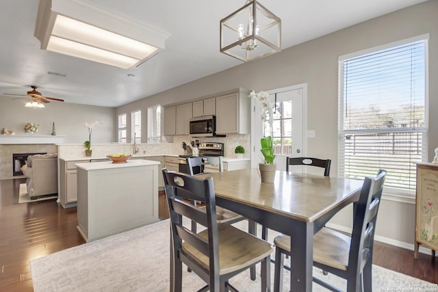 dining room with plenty of natural light, dark wood-type flooring, and ceiling fan with notable chandelier