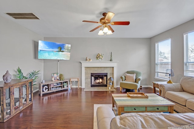 living room featuring visible vents, a ceiling fan, wood finished floors, a fireplace, and baseboards