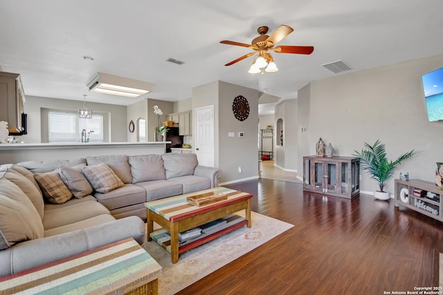 living room with visible vents, arched walkways, dark wood-style floors, and a ceiling fan