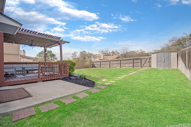 view of yard featuring a shed, a wooden deck, a fenced backyard, an outbuilding, and a pergola