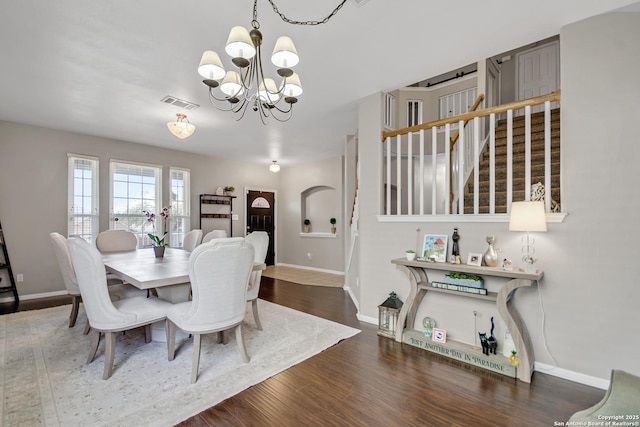 dining room with stairway, wood finished floors, baseboards, visible vents, and a chandelier