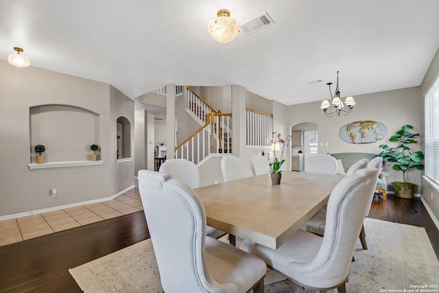 dining room featuring visible vents, stairway, wood finished floors, arched walkways, and a notable chandelier