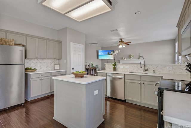 kitchen with a ceiling fan, a peninsula, dark wood-style flooring, a sink, and appliances with stainless steel finishes