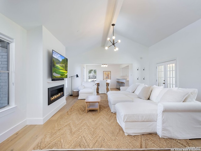 living area featuring baseboards, a chandelier, beamed ceiling, wood finished floors, and a glass covered fireplace