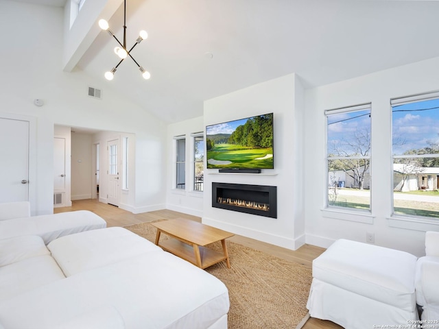 interior space featuring visible vents, baseboards, a chandelier, a lit fireplace, and light wood-style floors