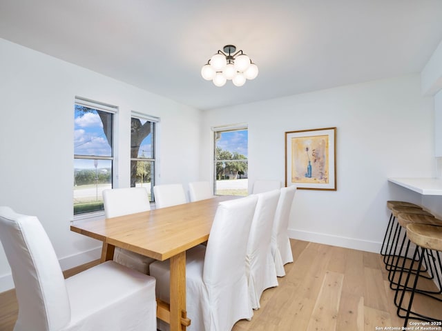 dining room featuring baseboards, light wood finished floors, and a chandelier