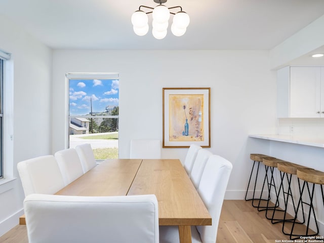 dining area featuring baseboards, light wood finished floors, and a chandelier