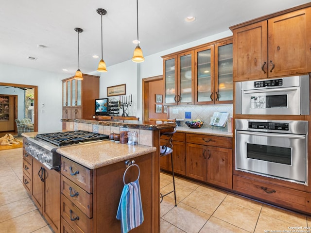 kitchen featuring brown cabinetry, light tile patterned floors, backsplash, and a kitchen island