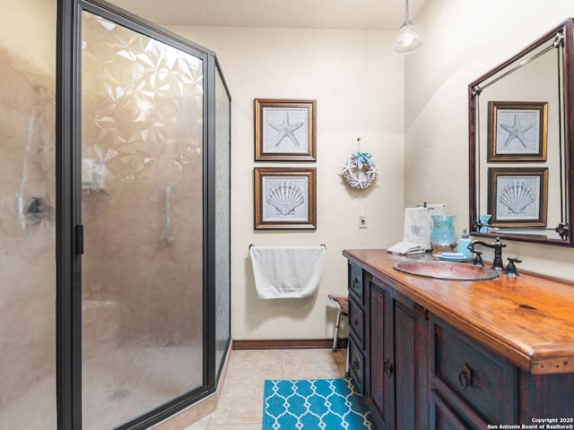 full bathroom featuring tile patterned flooring, vanity, a stall shower, and baseboards