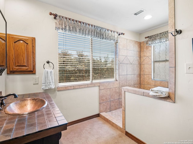 bathroom with visible vents, vanity, and walk in shower