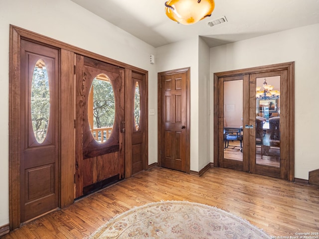 foyer entrance featuring visible vents, french doors, baseboards, and light wood-style floors