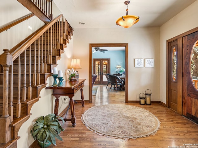 entrance foyer featuring french doors, stairs, baseboards, and wood finished floors