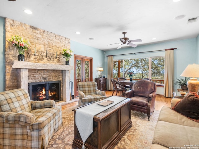 living area with light wood finished floors, visible vents, ceiling fan, a stone fireplace, and recessed lighting