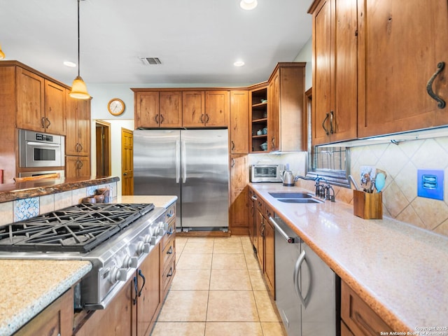 kitchen with visible vents, light tile patterned flooring, a sink, appliances with stainless steel finishes, and brown cabinets