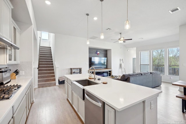 kitchen featuring visible vents, light wood-style flooring, a sink, stainless steel appliances, and backsplash