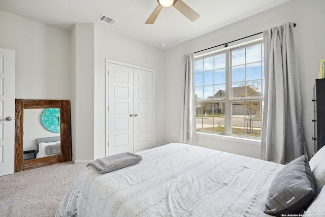 bedroom featuring a closet, a ceiling fan, visible vents, and carpet floors