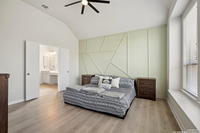 bedroom with wood finished floors, visible vents, lofted ceiling, ceiling fan, and ensuite bathroom