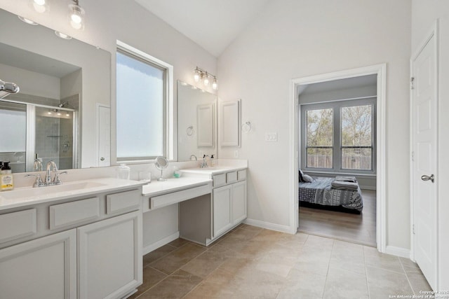 ensuite bathroom with tile patterned flooring, lofted ceiling, double vanity, a stall shower, and a sink