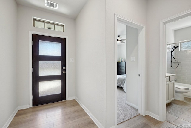 entryway featuring a ceiling fan, baseboards, visible vents, and light wood finished floors