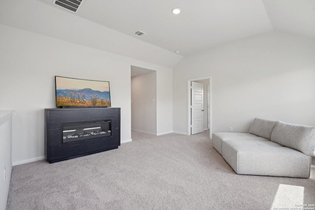 sitting room with a glass covered fireplace, vaulted ceiling, carpet, and visible vents