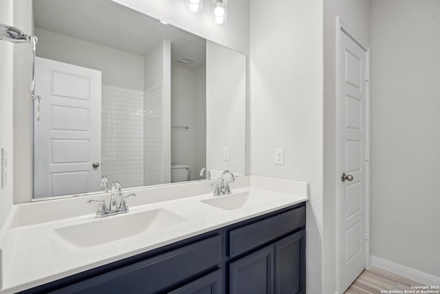 full bath featuring a sink, baseboards, toilet, and double vanity