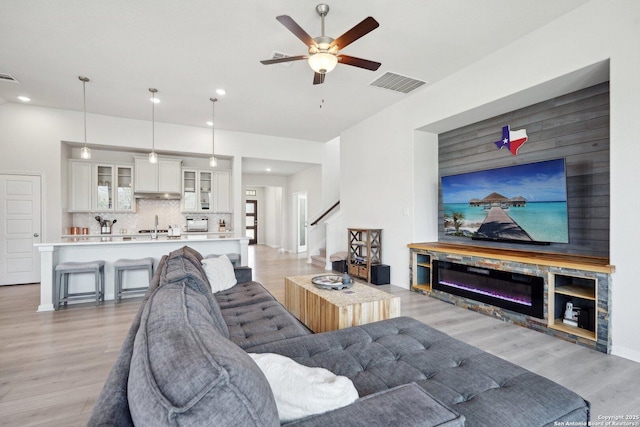 living area featuring stairs, light wood-style flooring, visible vents, and ceiling fan