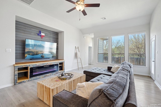 living area featuring light wood-style floors, a ceiling fan, visible vents, and baseboards