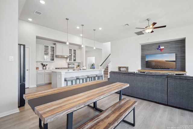 dining space with visible vents, light wood-style flooring, and a ceiling fan