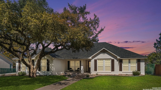 ranch-style house featuring brick siding, a porch, a front yard, and fence