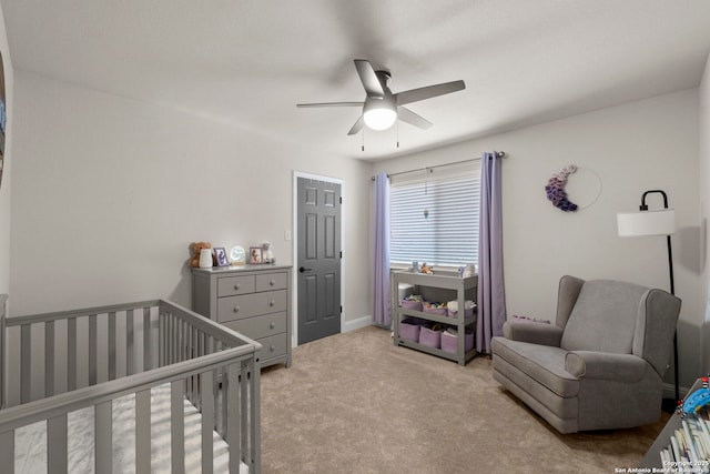 carpeted bedroom featuring a crib and ceiling fan