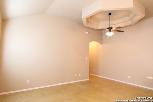 spare room with baseboards, a raised ceiling, arched walkways, and ceiling fan