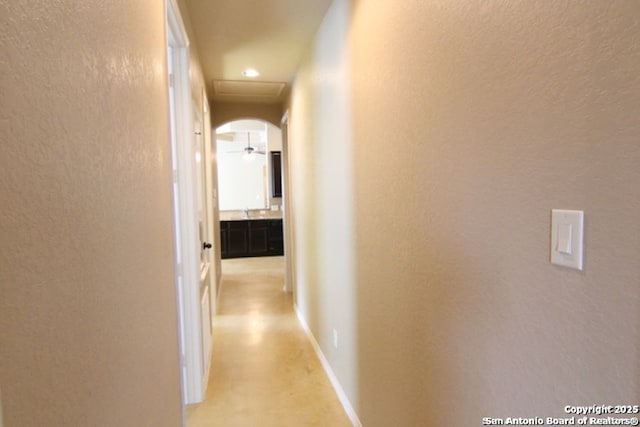 corridor with baseboards and arched walkways