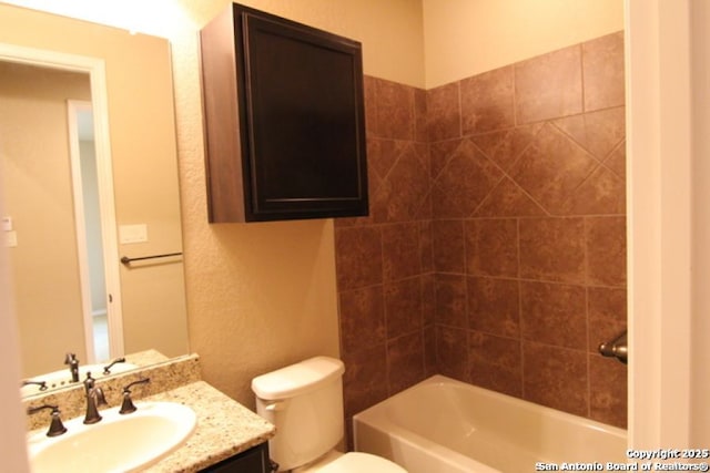 bathroom featuring shower / bathtub combination, toilet, vanity, and a textured wall