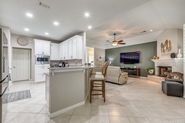 kitchen featuring stainless steel microwave, visible vents, a kitchen bar, and open floor plan