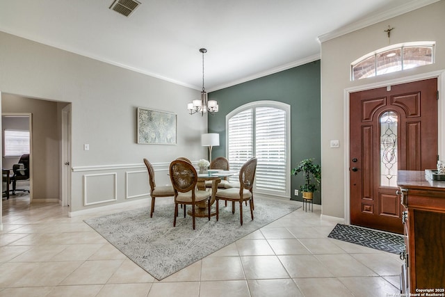 dining area with visible vents, a decorative wall, ornamental molding, light tile patterned flooring, and a notable chandelier