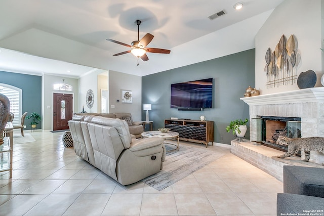 living room with visible vents, light tile patterned flooring, baseboards, a brick fireplace, and ceiling fan