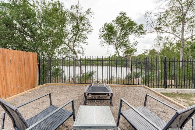view of patio featuring a fire pit, fence, and a water view