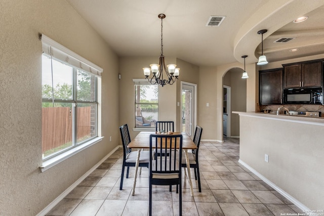 dining space featuring light tile patterned floors, arched walkways, visible vents, and a chandelier