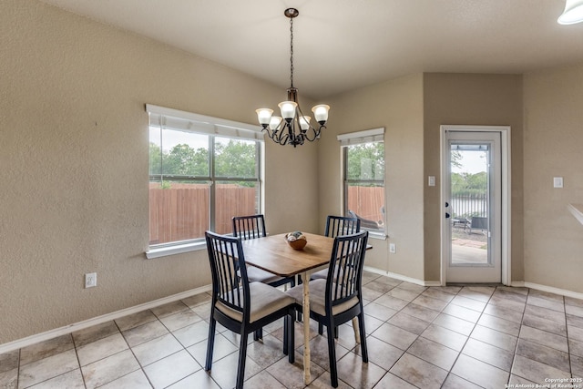 dining space featuring light tile patterned flooring, a textured wall, a wealth of natural light, and a chandelier