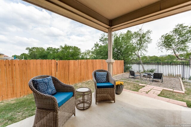 view of patio featuring a water view and a fenced backyard