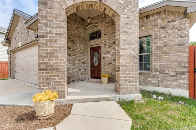 property entrance featuring brick siding, driveway, and an attached garage