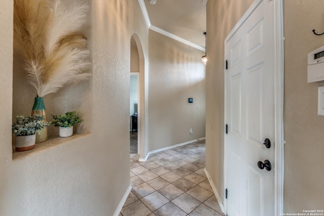 hall with baseboards, arched walkways, light tile patterned flooring, and crown molding