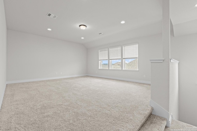 unfurnished room featuring visible vents, baseboards, carpet, and vaulted ceiling