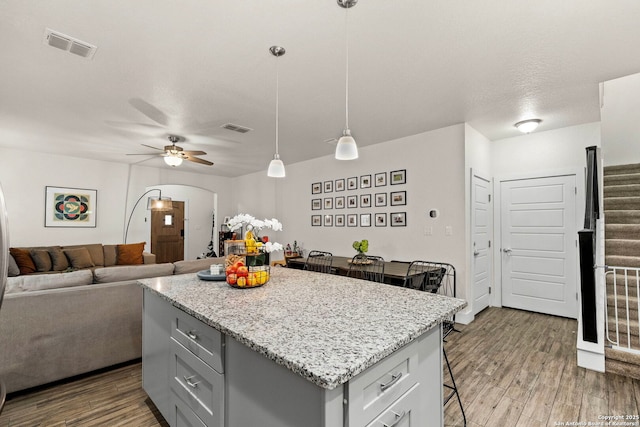 kitchen with visible vents, gray cabinets, a breakfast bar area, and wood finished floors