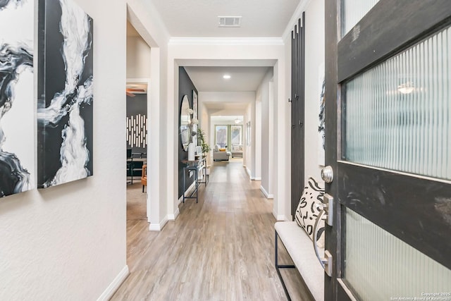 corridor with visible vents, baseboards, wood finished floors, and ornamental molding